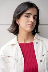 Chaqueta blanca de jean con cuello clásico, cierre frontal con botones metálicos y bolsillo de parche en el pecho. Presenta detalles de piedras de colores en el canesú.
