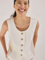 Chaleco de lino color crudo y beige con cuello redondo y cierre frontal con botones de madera.