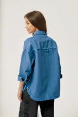 Sobrecamisa azul de jean con corte holgado, cuello camisero, cierre con botones a presión y dos bolsillos de parche en el pecho.