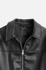Cazadora negra relaxed fit confeccionada en tejido efecto piel. Tiene cuello solapa, manga larga con puño abotonado, bolsillos de vivo en cadera, bolsillo interior, bajo con elástico y cierre frontal de cremallera.