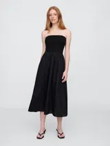 Vestido midi strapless color negro, con elástico en el busto y falda amplia.