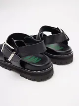 Sandalias negras tipo gladiador con plataforma de goma y hebilla metálica.