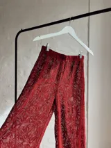 Pantalón acampanado de encaje color borgoña con diseño floral.