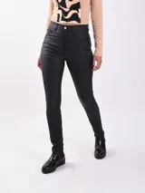 Pantalón chupín de cuero sintético color negro, tiro alto y corte ajustado.