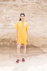 Vestido corto color mostaza, de corte recto y cuello mao con abertura parcial abotonada.