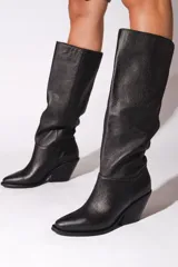 Bota de cuero vacuno color negro, con caña alta, punta fina y taco de 6.5cm.