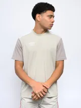 Remera de mangas cortas color beige con cortes y cambios de color en hombros y mangas. Logo de la marca Umbro estampado en el pecho.