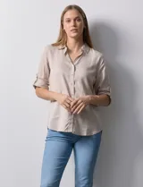 Camisa color beige de tencel, marca Hester & Orchand. Cuello con solapa, escote en V y abertura central con botones. Delantera con bolsillos. Largo de manga regulable con presilla y botón.