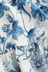 Vestido corto de viscosa con estampado floral en tonos azules. Tiene cuello mao, botones frontales, mangas largas abullonadas con puños abotonados y falda con volantes.