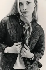 Campera negra de mangas largas con corte amplio, nylon relleno con matelassé de corazones y bolsillos con solapa y botones snap en el frente.