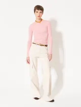 Remera rosa de punto con textura suave, mangas largas, escote redondo y espalda amplia y abierta.