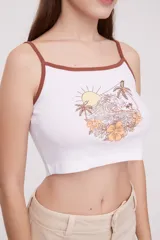 Musculosa cropped blanca con tirantes marrones, estampado de playa con palmeras, sol y flores.