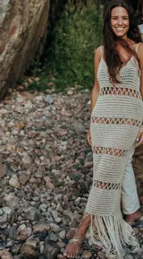 Vestido largo tejido a crochet color crudo, con breteles finos y diseño calado. Presenta flecos en el ruedo.