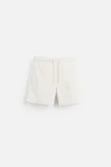 Bañador corto color blanco hueso de tejido técnico, con cintura elástica ajustable con cordón, bolsillos laterales y trasero.
