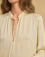 Vestido largo color crema, con cuello mao con lazo ajustable, mangas largas amplias y tajos laterales.