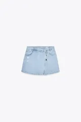 Falda pantalón de tiro alto de denim celeste con efecto lavado y roturas frontales. Tiene cinco bolsillos y cierre frontal con cremallera oculta y botones.
