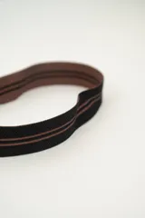 Bolso tipo bombonera tejido a crochet, con patrón geométrico en tonos rosa y marrón. Tiene cierre con cordón ajustable y correa de hombro.