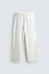 Pantalón negro de corte relajado y pierna ancha, confeccionado en mezcla de algodón y lino. Presenta cintura elástica ajustable con cordón y cierre frontal con cremallera y botón.