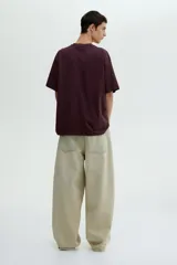 Remera color bordó de corte holgado con cuello redondo y mangas cortas. Estampado frontal con la frase "Handle with care".