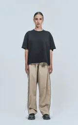 Pantalón deportivo beige de nylon con cintura elástica ajustable con cordón, corte amplio y aberturas laterales con broches.