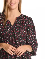 Blusa de gasa estampada en color negro con motivos rojos y blancos, de cuello a la base con escote en V y manga larga con terminación fruncida.