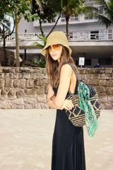 Bolso tote tejido en raffia color negro y beige, con vivos y correas en cuero sintético negro. Tiene cierre interno con snap metálico y forro de algodón.