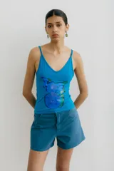 Musculosa celeste elastizada con estampado abstracto en el frente.