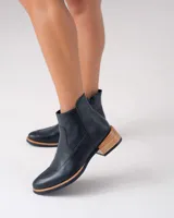 Botas cortas negras de cuero vacuno con cierre lateral YKK, taco de madera foliado en cuero de 3cm, entre suela de goma de 1cm, inclinación de horma de 2cm y caña de 12cm.