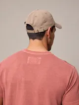 Gorro con visera color beige confeccionado en lona de algodón con logo bordado en el frente.