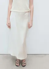 Falda midi color crema de tejido satinado, corte recto y cintura elástica.