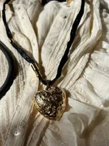 Collar dorado con dije de corazón con diseño floral y cinta de satén negra.