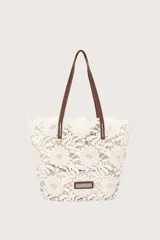 Bolso tipo tote de encaje floral blanco con forro color crema y asas de cuero marrón.