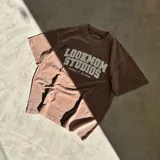 Camiseta oversize marrón con efecto acid wash y estampado frontal blanco con la leyenda "Lookmom Studios".