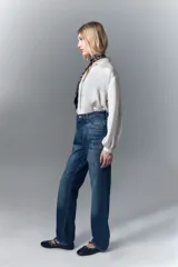 Jean de tiro alto y calce recto, confeccionado en denim azul rígido. Presenta un diseño de hotfix brillante en forma de guitarra en el frente de la pierna derecha.