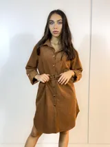 Sobre camisa marrón con cuello camisero, cierre frontal con botones y cinturón con hebilla metálica.