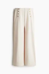 Pantalón de vestir color crema, de tiro alto y corte palazzo, con detalle de doble botonadura dorada en la parte superior.