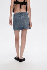 Minifalda de jean azul con lavado medio, corte recto y detalles de strass en bolsillos y laterales.