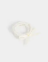 Set de cinco pulseras elásticas de perlas blancas con cinta de raso color crema.