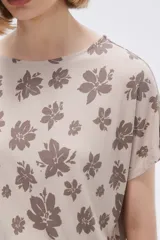 Remera blanca con estampado floral en color lila, de corte holgado y mangas cortas.