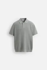 Polo gris de punto con textura, corte regular, cuello solapa y cierre frontal con botones.