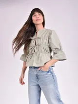Blusa color verde oliva con escote con lazos, mangas 3/4 con volados y corte a la cintura.