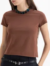 Remera marrón de punto liso elastizado, con escote redondo a la base y mangas cortas. Tiene el logo JCH bordado en la espalda y un fit al cuerpo.