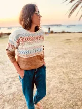 Sweater de lana merino color tostado, con cuello redondo y mangas largas. Presenta un diseño geométrico con motivos étnicos en tonos beige, azul y naranja.