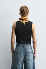 Musculosa blanca de algodón con cuello redondo y sisas amplias, corte ajustado.