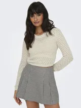 Sweater corto color crema, tejido a crochet con cuello redondo y mangas largas.