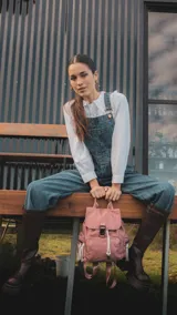 Mochila de nylon color rosa con tapa y broche metálico. Tiene apertura superior con cierre marinero, bolsillos internos, bolsillo con cierre metálico al frente y laterales, asas rígidas de mano y correas regulables para colgar en la espalda.