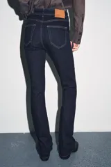 Pantalón de jean azul oscuro, de tiro bajo, corte slim fit y bootcut. Con cinco bolsillos y cierre frontal con cremallera y botón.