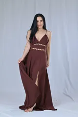 Vestido largo de fiesta color marrón chocolate, con breteles finos, escote en V y tajo lateral. Presenta detalle de doble abertura en la cintura con apliques de argollas doradas.