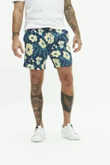 Short de baño azul con estampado de flores amarillas y hojas verdes. Cintura elástica con cordón ajustable, dos bolsillos laterales y uno trasero.