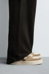 Zapatillas deportivas de estilo retro, color beige y marrón, con cordones y suela gruesa.